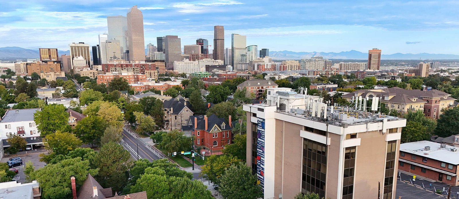 Aerial view of city street with trees and buildings, mountain horizon in the distance