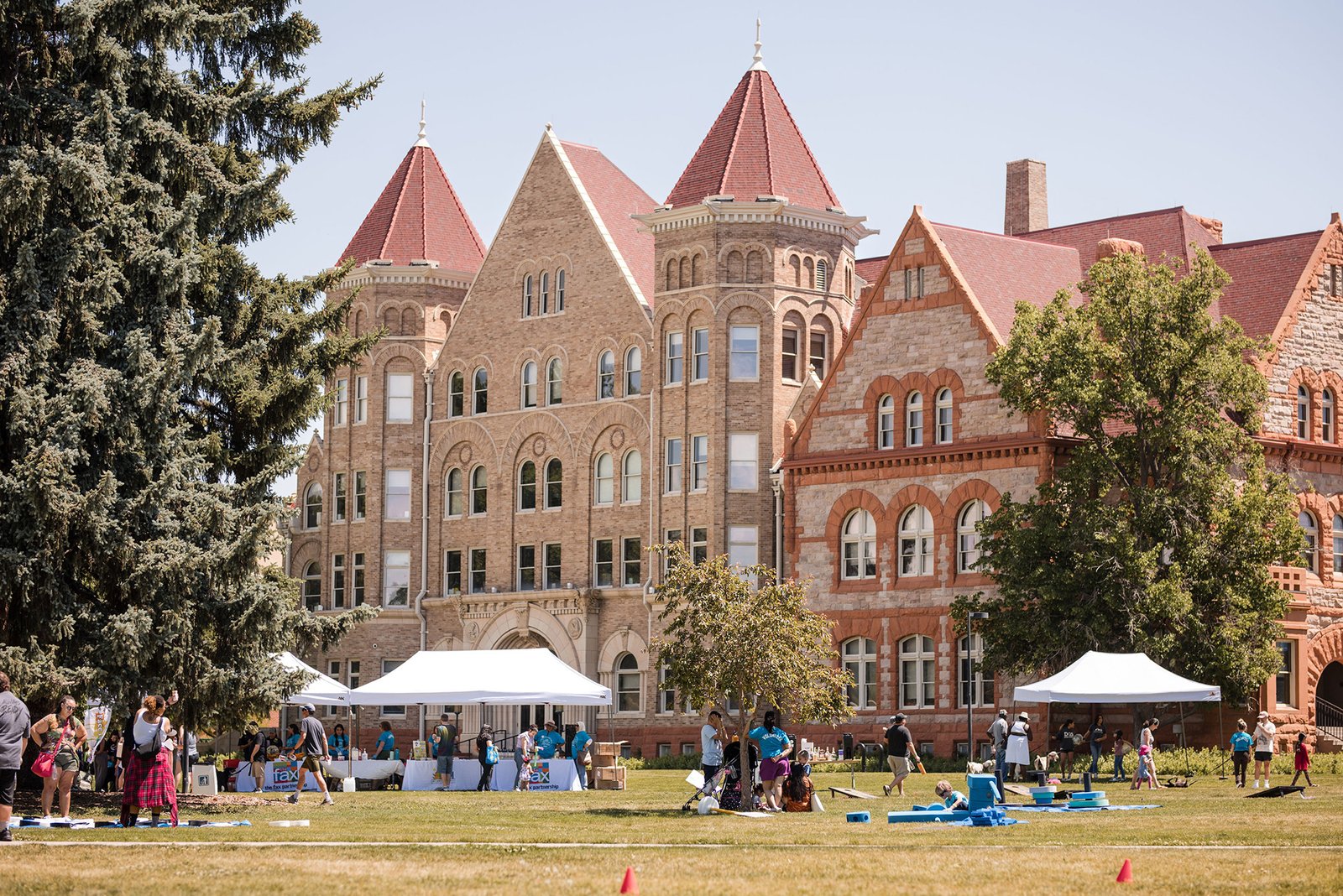 Mosaic Community Campus exterior. White tents strewn across a grassy exterior. Students walking around.
