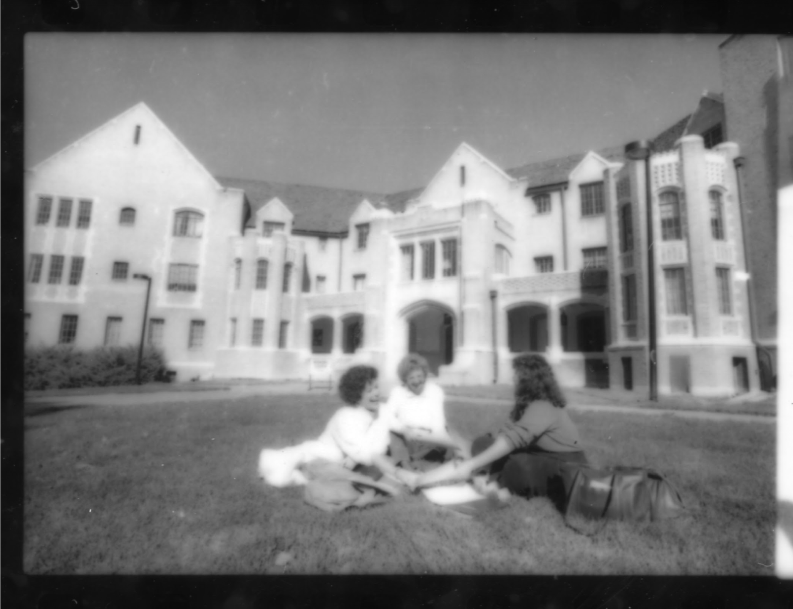 black and white photo of students on grass in front of building