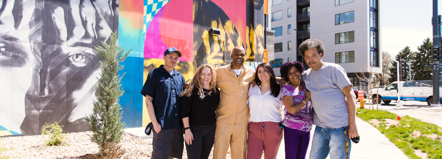 6 people standing arm-in-arm in front of wall art