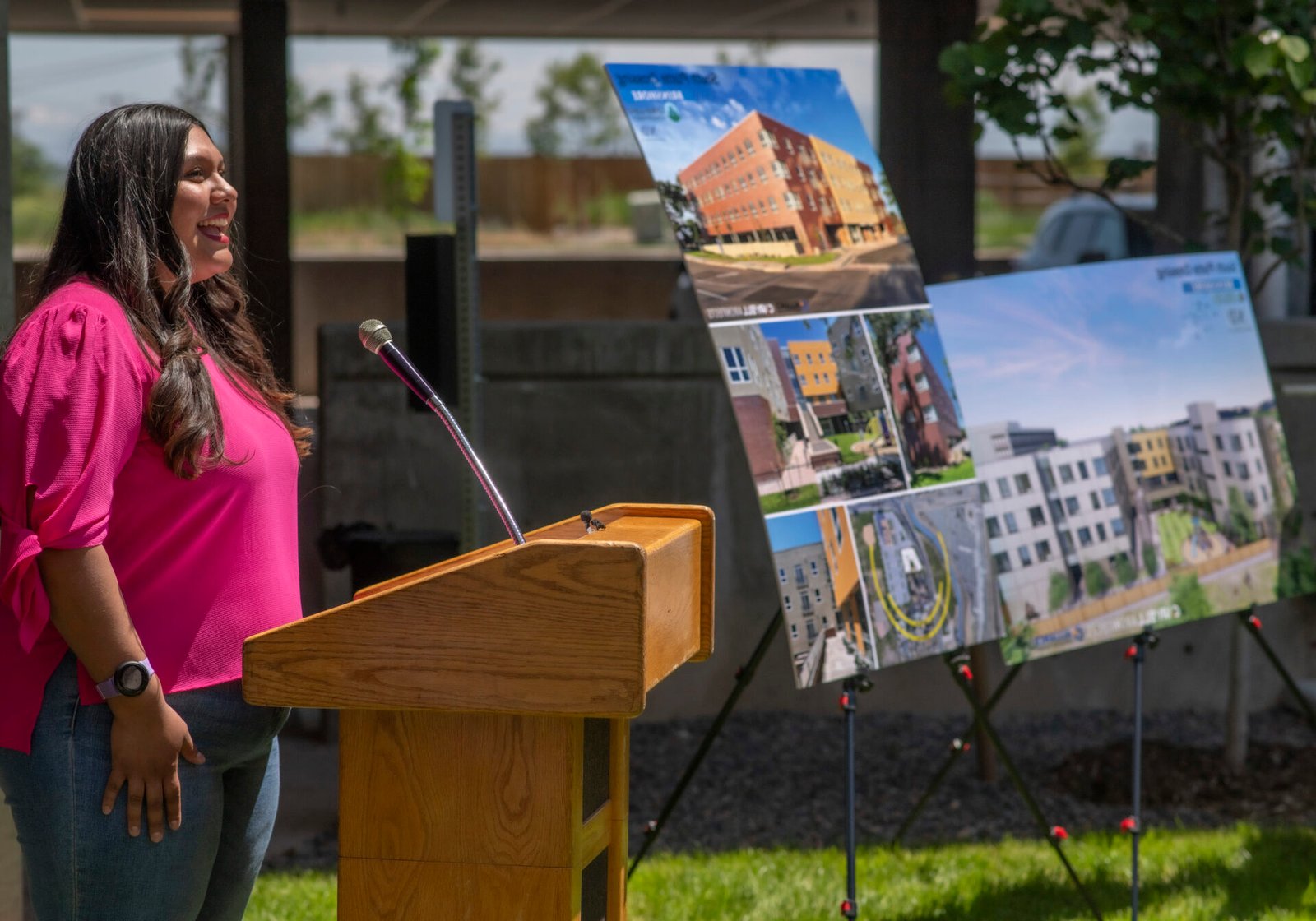 a woman stands beside posters showing an apartment building