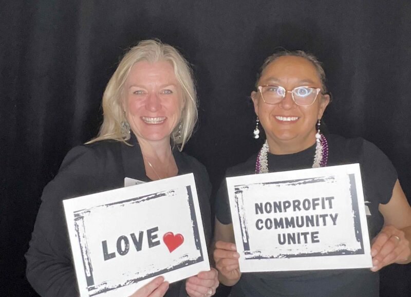 two women holding signs that say "love" and "nonprofit community unite"