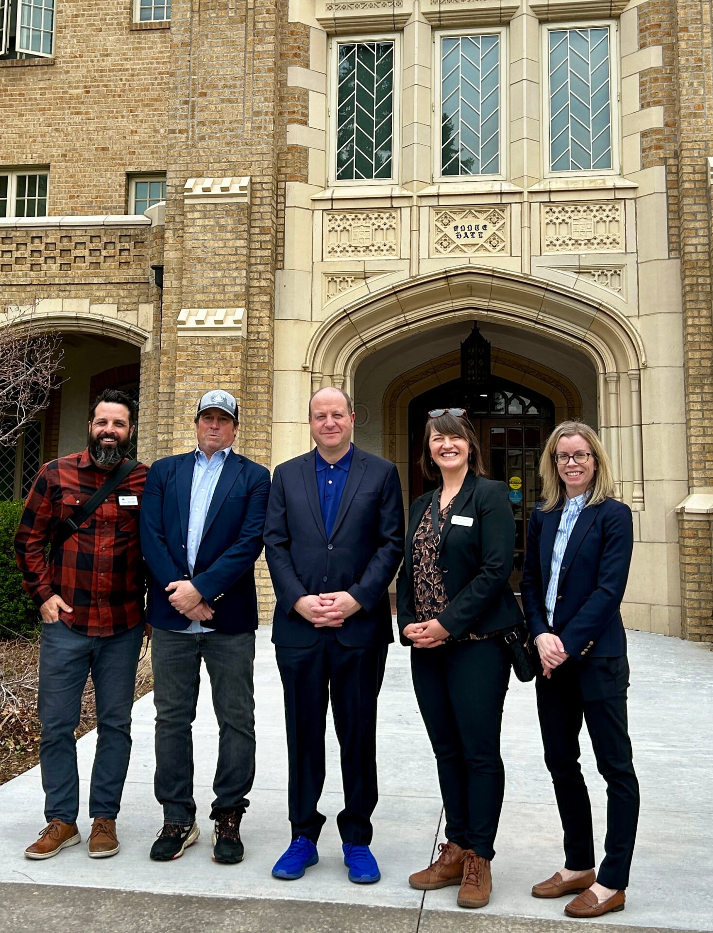 five people standing in front of a historic building; includes governor jared polis