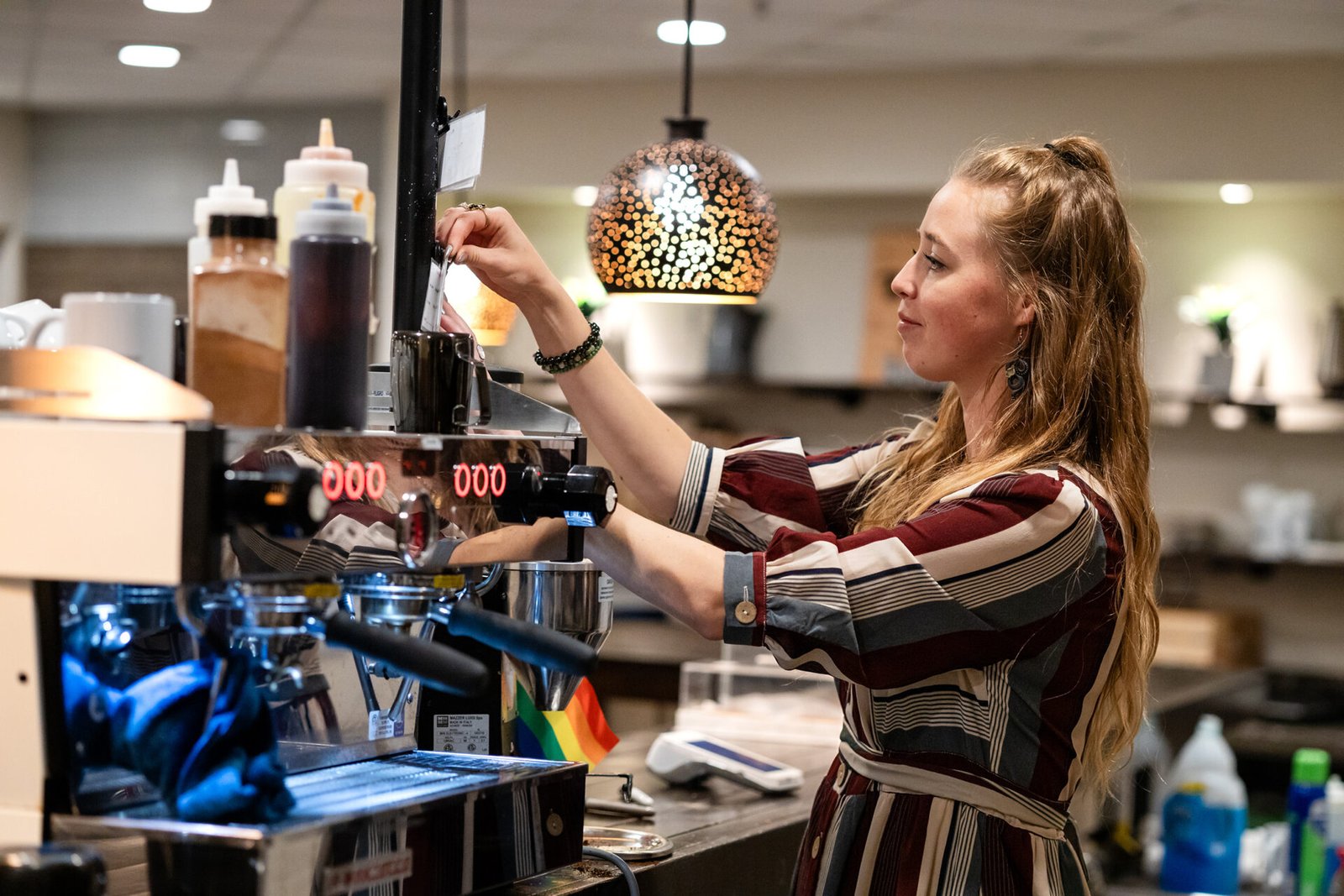 a woman pulls espresso in a coffee shop